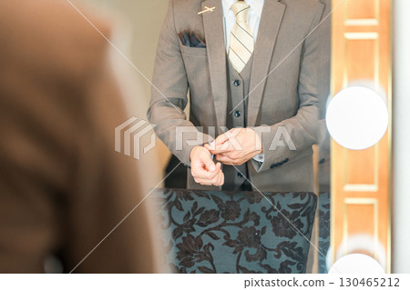 A groom in a suit or tuxedo getting ready in the bridal room of a wedding venue 130465212
