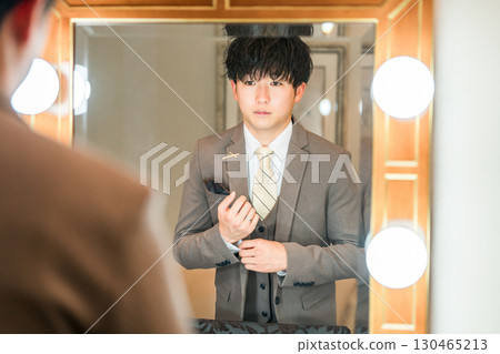 A groom in a suit or tuxedo getting ready in the bridal room of a wedding venue A groom in a suit or tuxedo getting ready in the bridal room of a wedding venue 130465213