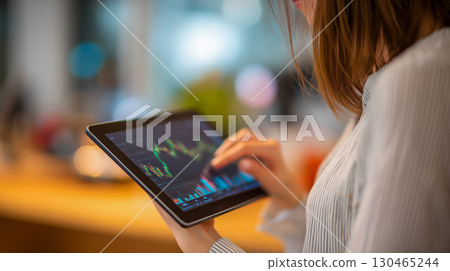 一位女士在室內辦公風格的商業場景中,用平板電腦查看股票圖表,專注於投資分析 一位女士在室內辦公風格的商業場景中,用平板電腦查看股票圖表,專注於投資分析 130465244