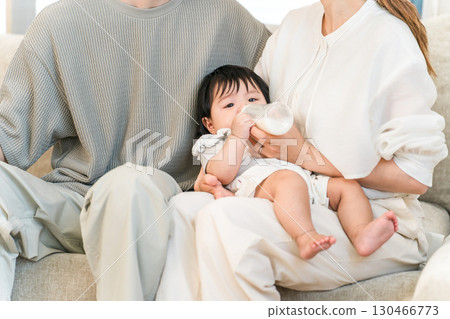 Baby drinking milk from a bottle on the sofa at home, infant Baby drinking milk from a bottle on the sofa at home, infant 130466773