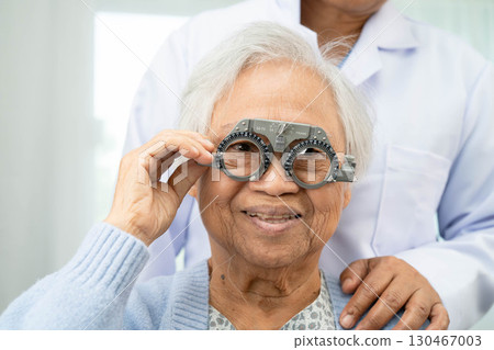 Optometrist checking Asian elderly woman ophthalmic vision eye test and using optical trial frame. Optometrist checking Asian elderly woman ophthalmic vision eye test and using optical trial frame. 130467003