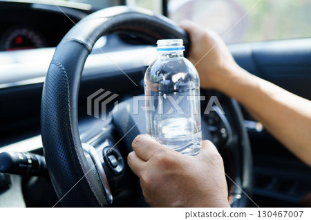 Asian woman driver holding water bottle in car. 130467007