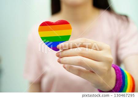 Asian woman holding LGBT heart with rainbow flag. 130467295