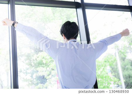 Businessman taking a break by the window, stretching and taking a deep breath, back view without face Businessman taking a break by the window, stretching and taking a deep breath, back view without face 130468930