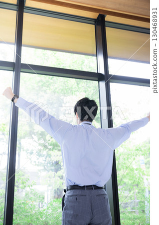 Businessman taking a break by the window, stretching and taking a deep breath, back view without face Businessman taking a break by the window, stretching and taking a deep breath, back view without face 130468931