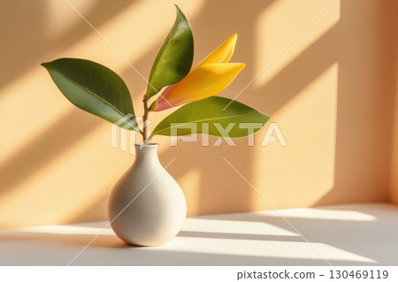 Yellow flower in a vase with leaves illuminated by sunlight on a soft background 130469119