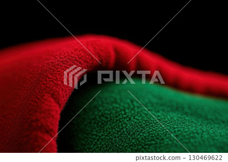 Vibrant red and green fabric drapes elegantly against a dark background with textured folds 130469622