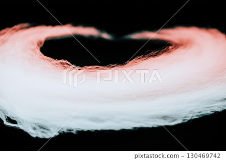 Swirling white and pink smoke creates a heart shape against a dark background 130469742