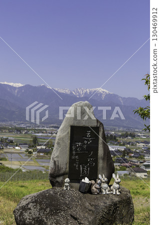 A stone monument and rabbit figurine overlooking snow-capped mountains and rural scenery A stone monument and rabbit figurine overlooking snow-capped mountains and rural scenery 130469912