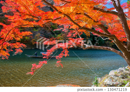 Boatman punting tourist boat along Arashiyama river in autumn 130471219
