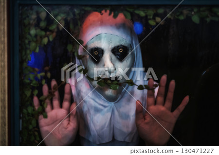 Scary devilish nun look through window at night.Haloween 2025 130471227