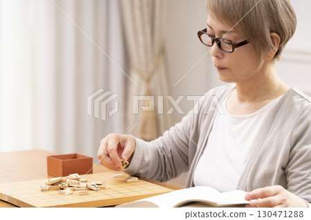 A senior woman practicing her hobby of shogi alone 130471288