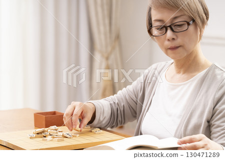 一位老年婦女獨自練習將棋 一位老年婦女獨自練習將棋 130471289