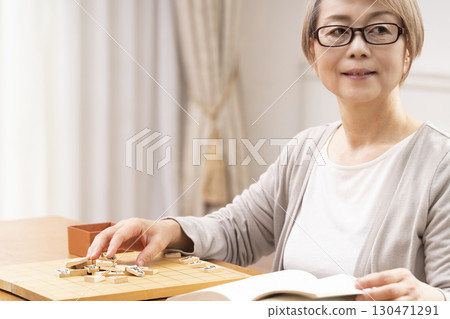 一位老年婦女獨自練習將棋 一位老年婦女獨自練習將棋 130471291
