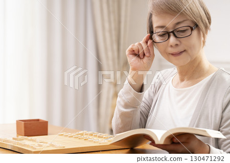 A senior woman practicing her hobby of shogi alone A senior woman practicing her hobby of shogi alone 130471292