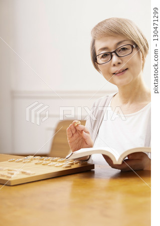 A senior woman practicing her hobby of shogi alone 130471299