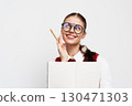 Smiling student with glasses holding a notebook and a pencil, looking thoughtful against a white background Engaging expression indicating creativity and inspiration 130471303