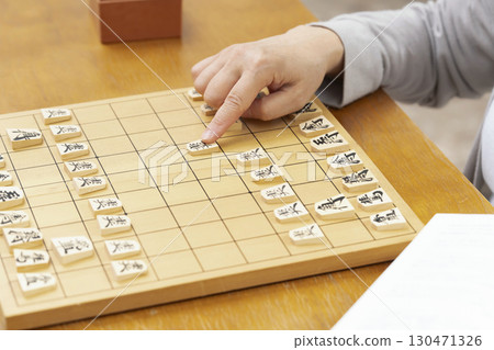 一位老年婦女獨自練習將棋愛好的手 一位老年婦女獨自練習將棋愛好的手 130471326