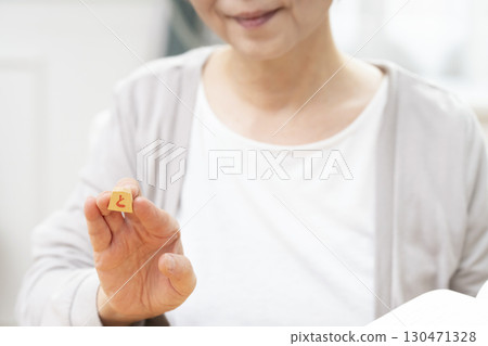 一位老年婦女獨自練習將棋愛好的手 一位老年婦女獨自練習將棋愛好的手 130471328