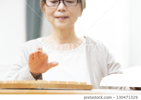 一位老年婦女獨自練習將棋愛好的手 一位老年婦女獨自練習將棋愛好的手 130471329