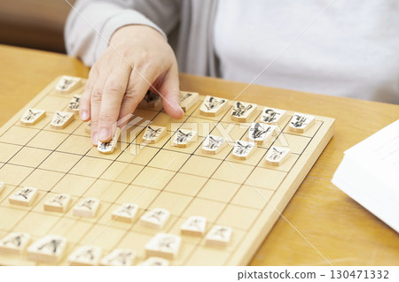 一位老年婦女獨自練習將棋愛好的手 一位老年婦女獨自練習將棋愛好的手 130471332