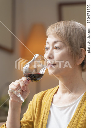 Senior woman relaxing in the living room drinking wine 130471591