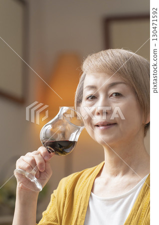 Senior woman relaxing in the living room drinking wine Senior woman relaxing in the living room drinking wine 130471592