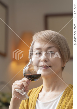 Senior woman relaxing in the living room drinking wine Senior woman relaxing in the living room drinking wine 130471593