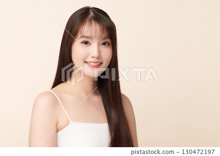 A beautiful young Asian woman with clean, fresh skin against a beige background. Skincare, facial treatment, cosmetology, beauty, and spa. An elegant portrait of an Asian woman. A beautiful young Asian woman with clean, fresh skin against a beige background. Skincare, facial treatment, cosmetology, beauty, and spa. An elegant portrait of an Asian woman. 130472197