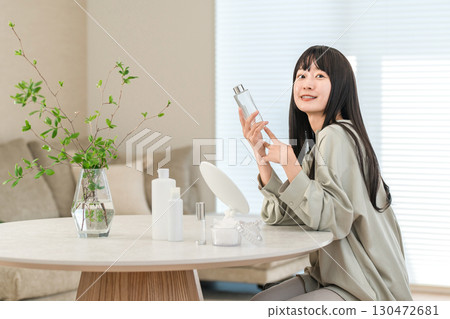 一位年輕的亞洲女性使用基本化妝品來保濕、護膚和抗衰老。 一位年輕的亞洲女性使用基本化妝品來保濕、護膚和抗衰老。 130472681