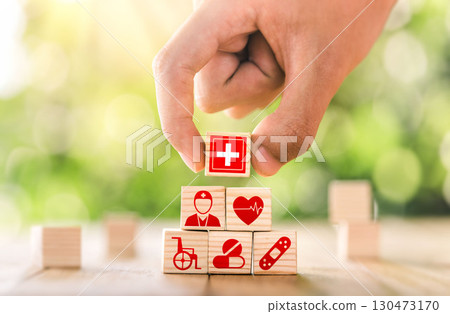 Hand arranged wooden blocks with icons of medical health. health insurance for your health concept. Healthcare medical business. Hand arranged wooden blocks with icons of medical health. health insurance for your health concept. Healthcare medical business. 130473170