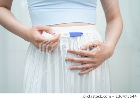 Asian holding pregnancy test for female of ovulation day, fetus, maternity, childbirth, birth control. 130473544