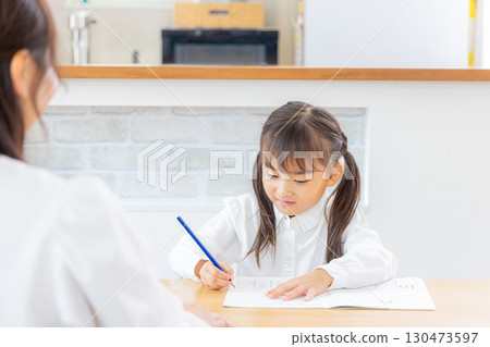 A girl and her mother studying in the living room A girl and her mother studying in the living room 130473597