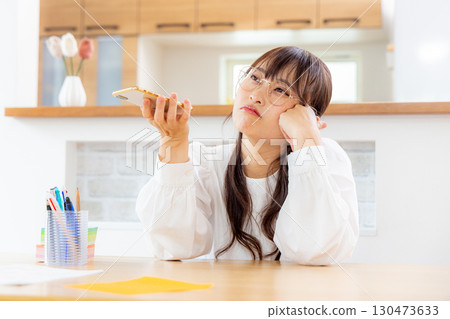 A woman thinking while watching a smartphone A woman thinking while watching a smartphone 130473633