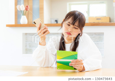 Annoyed woman looking at a passbook Annoyed woman looking at a passbook 130473643