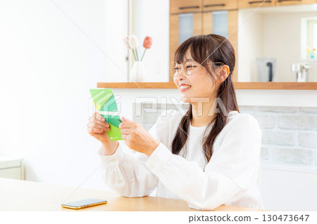 A woman checking her bankbook with a smile A woman checking her bankbook with a smile 130473647