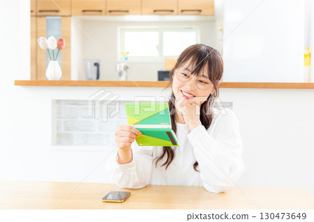 一位女士微笑著查看她的存摺 130473649