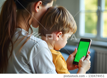 Mom is using a cell phone and spending time with her cute baby boy. Working from a flat. Female freelancer connecting to internet via netbook. She checks her mailbox at morning. Be online everytime. 130474451