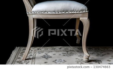 Elegant upholstered chair on ornate rug dark background 130474663