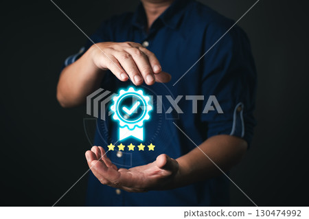 A person in a dark blue shirt presents a glowing certificate icon with a checkmark and five stars, symbolizing quality assurance and trust in digital standards, service, or performance. A person in a dark blue shirt presents a glowing certificate icon with a checkmark and five stars, symbolizing quality assurance and trust in digital standards, service, or performance. 130474992
