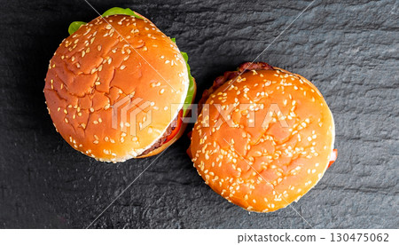 macro photo of three hamburgers_on black kitchen granite surface top view 130475062