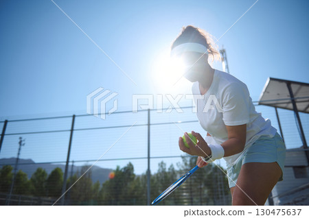 Female Tennis Player Preparing to Serve on a Sunny Outdoor Court 130475637