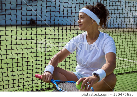 Female Tennis Player Relaxing on Court After an Intense Practice Session Female Tennis Player Relaxing on Court After an Intense Practice Session 130475683