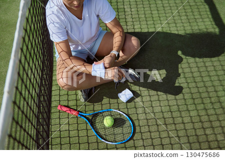 Athlete Resting on Tennis Court with Racket and Ball During Practice Athlete Resting on Tennis Court with Racket and Ball During Practice 130475686