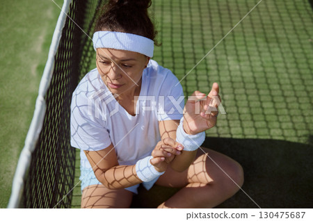 Young Woman Resting on Tennis Court in Sunlight Young Woman Resting on Tennis Court in Sunlight 130475687