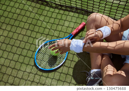 Tennis Player Resting on Court with Racket, Ball, and Wristbands Tennis Player Resting on Court with Racket, Ball, and Wristbands 130475688