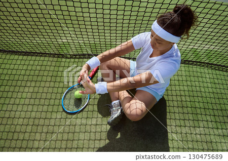 Young Female Tennis Player Taking a Break on Court 130475689