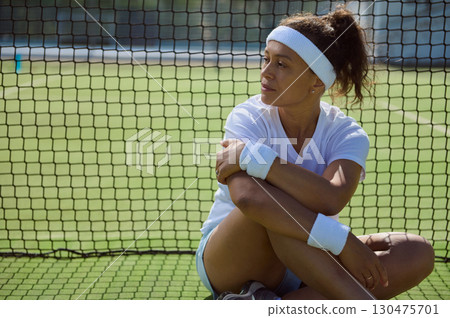 Female Tennis Player Resting by the Net on a Sunny Day Female Tennis Player Resting by the Net on a Sunny Day 130475701