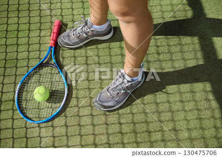 Tennis Gear and Legs of Player on Court Close-Up on Sunny Day 130475706