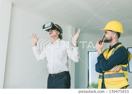 Construction manager happy using VR visual presentation technology device present by builder at site Construction manager happy using VR visual presentation technology device present by builder at site 130475833